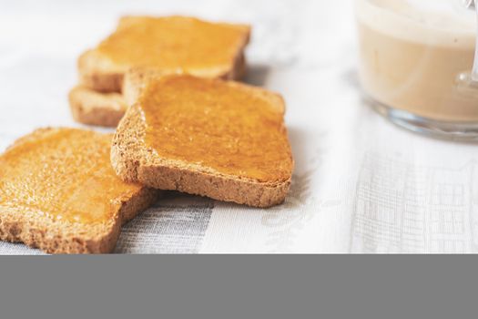 group of biscuits with jam spread with a cup of cappuccino on a table with the decorated tablecloth. Morning breakfast. Healthy food and lifestyle