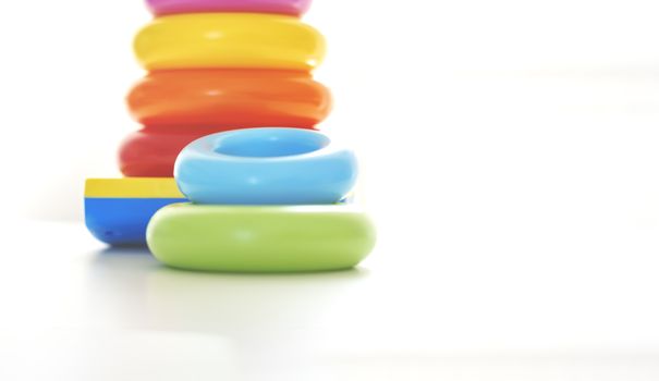 Colorful plastic rings on a white background to be stacked in a tower. Toy for newborns.