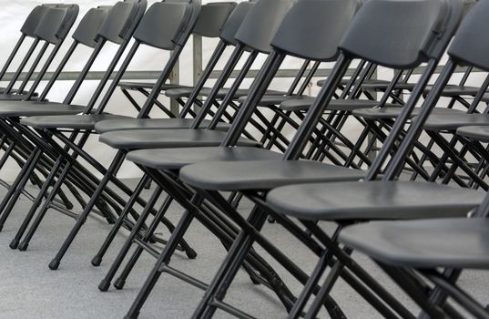 numerous folding chairs arranged in a row in a conference room.