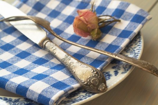 Vintage blue and white dinner plates, ornate vintage silver cutlery with dry rose