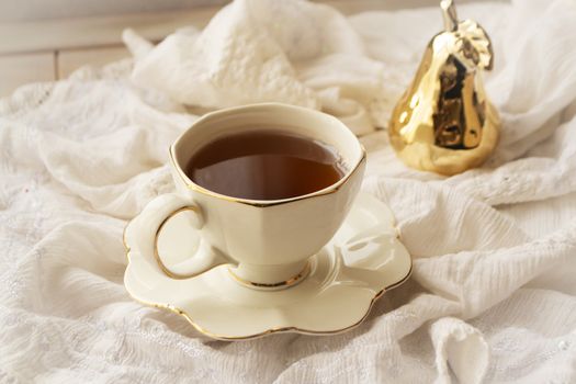 porcelain tea cup with golden decoration on white vintage napkin