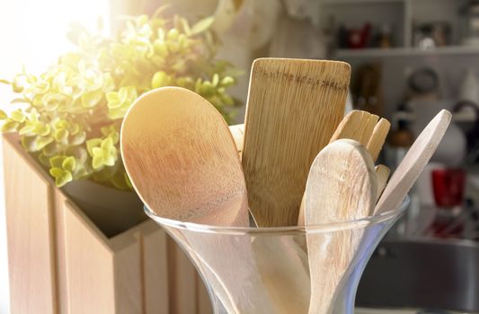 Close-up view of a group of wooden kitchen utensils inside a glass container. Cooking with traditional utensils