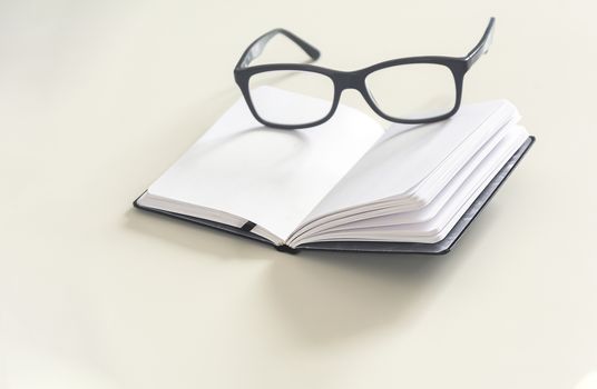 a pair of eyeglasses on an open notebook with blank pages. Office and study. Pages yet to be written