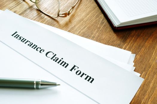 Insurance claim form with pen on wooden surface.