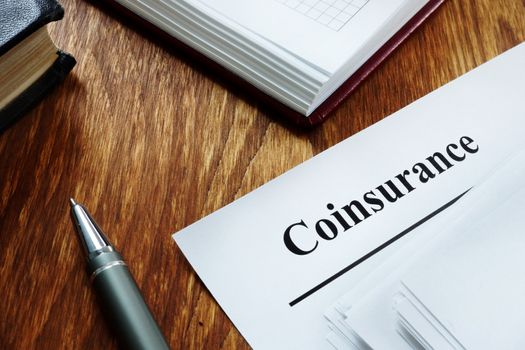 Coinsurance concept. Stack of insurance documents on desk.