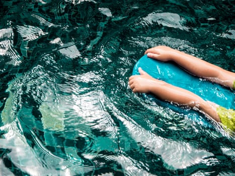 Child with foam kickboards swimming in the pool