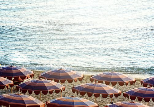 Sun umbrellas open early in the morning on a beach by the sea. Beach holidays during the summer season.