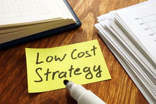 Low cost strategy sign and stack of papers.