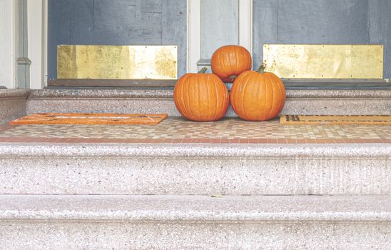 three pumpkins at the end of a staircase of a residential house. Halloween decorations