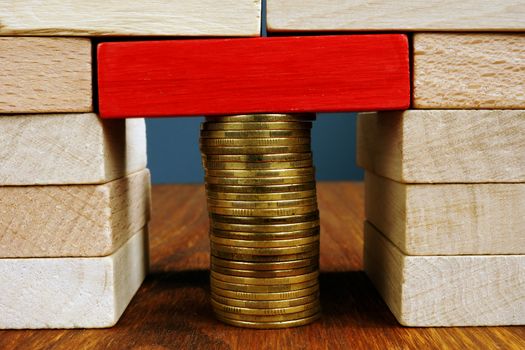 Stack of coins holds wooden blocks. Financial balance and stability.