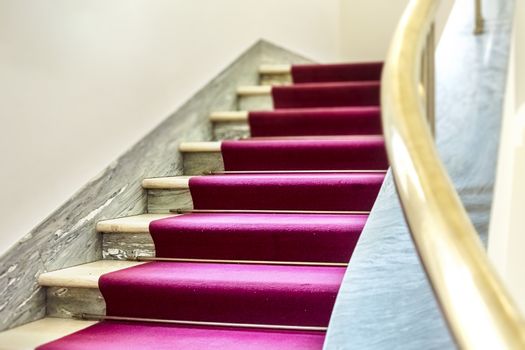 elegant staircase with a purple velvet carpet on the steps and a brass handrail. Elegance and luxury. Events and awards