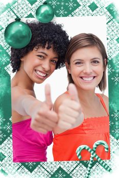 Smiling teenage girls proudly showing their thumbs up against a white background against christmas frame