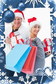 Festive mature couple in winter clothes holding gifts and bags against christmas frame