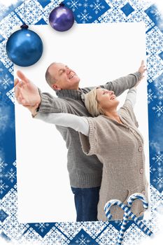 Happy mature couple in winter clothes against christmas frame