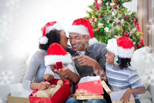 Happy family having fun with Christmas presents against snowflakes