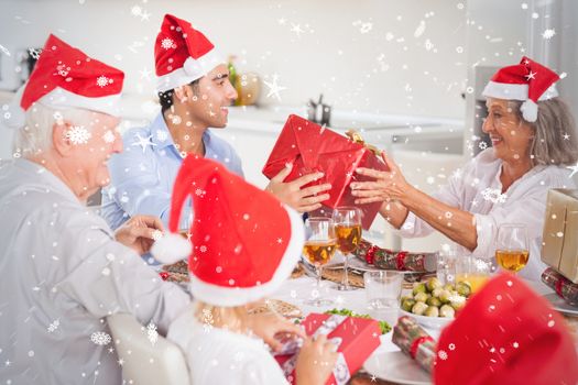 Composite image of Happy family exchanging christmas gifts against snow falling