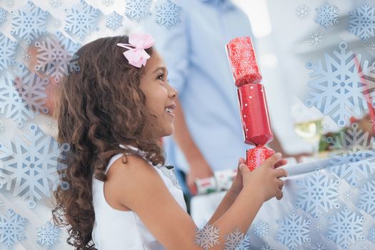 Cute little girl holding crackers against snowflake frame