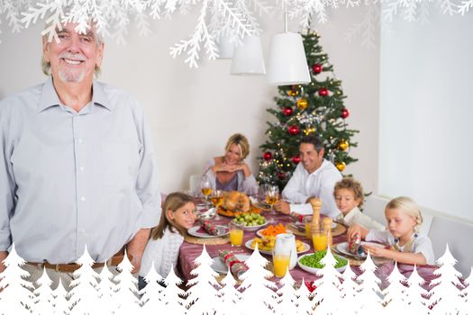 Smiling grandfather standing at the dinner table against fir tree forest and snowflakes