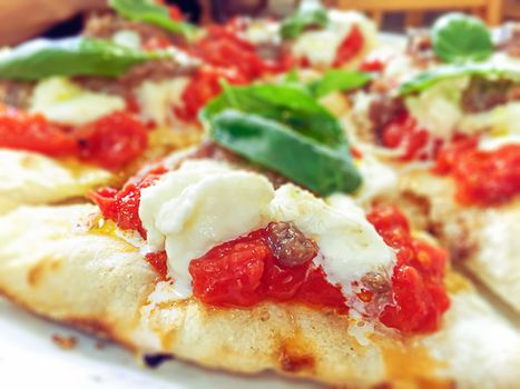 close-up view of a margherita pizza with fresh tomatoes, mozzarella cheese and basil leaves. Typical Neapolitan and Italian recipe