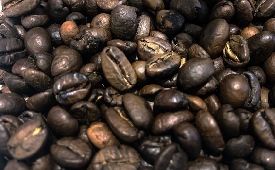 large group of raw roasted brown coffee beans stored in a container and then ground. Blurred and shallow depth of field. Close up view. Agriculture and organic products