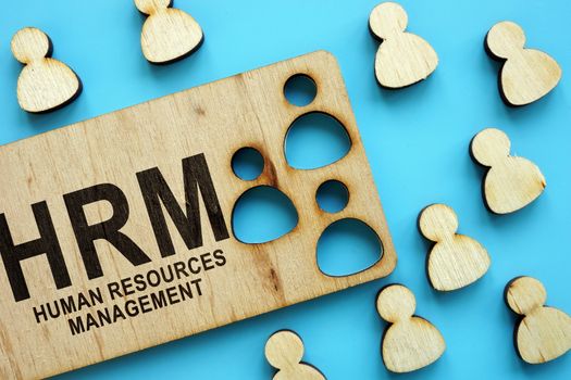 HRM human resources management concept. Wooden figures on the blue background.