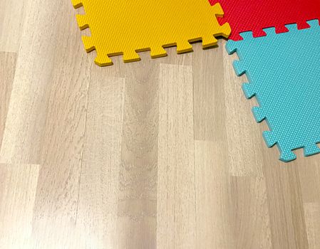 Soft rubber mat composed of colored blocks intersected with each other on a wooden floor. Suitable for children to play or for yoga exercises. Interior shot
