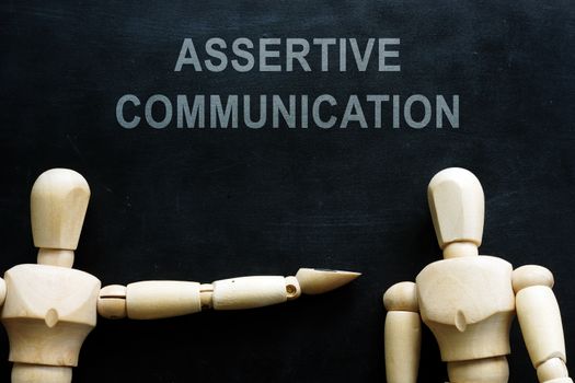 Assertive communication phrase and two wooden figures.