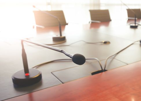 tabletop microphone on a wooden table in a boardroom. Natural light coming in through the window. Meetings and conferences