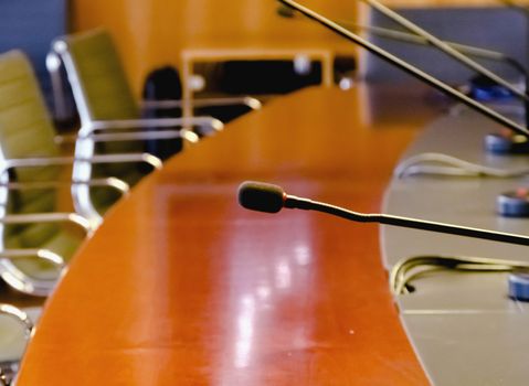 a table microphone in a board room with a wooden table and a row of empty chairs. Business and management concept. Board of directors