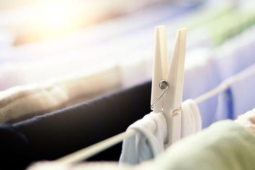 a white clothespin holds a dress hanging on a drying rack to dry. Sunlight beam coming from the window. Household chores and laundry
