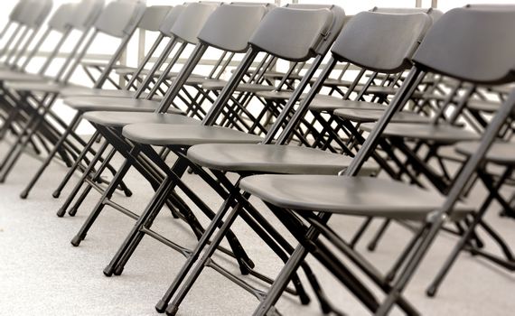 a group of black folding chairs arranged in a row for a convention