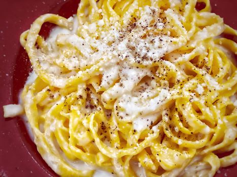 A portion of Italian traditional pasta with cacio e pepe - cheese and pepper- sauce served with grated Parmesan on top