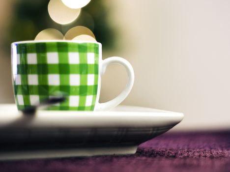a cup of coffee with green stripes on a purple fabric surface. The bokeh effect on the back seems to come out of the cup.
