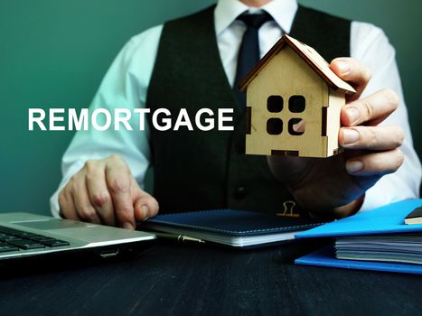 Man holds wooden home and sign remortgage.