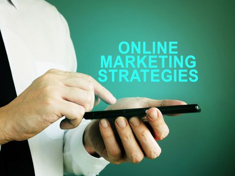 Businessman with smartphone and sign online marketing strategies.
