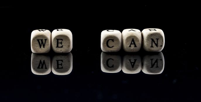 wooden blocks with the text we can on a black background