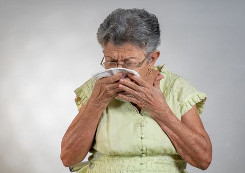 An old woman sneezing and covering his mouth and nose