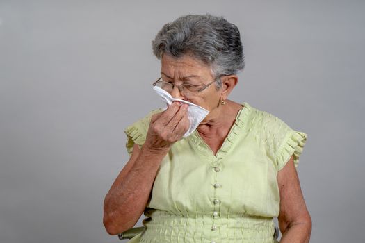 An old woman sneezing and covering his mouth and nose