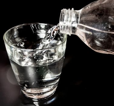 Pour water from the bottle into the glass