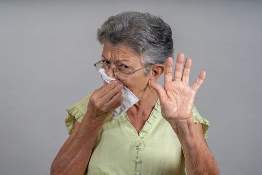 An old woman sneezing and covering his mouth and nose