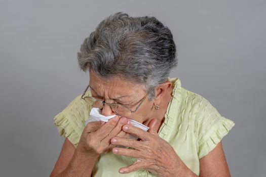 An old woman sneezing and covering his mouth and nose