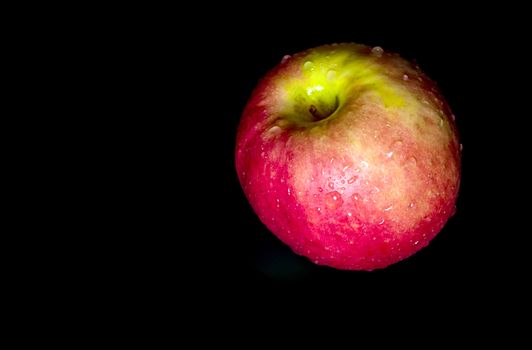 Water droplet on glossy surface of freshness red apple on black background