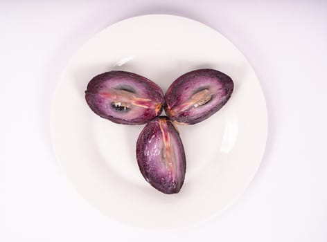 Three pieces of caimito fruit on a white plate