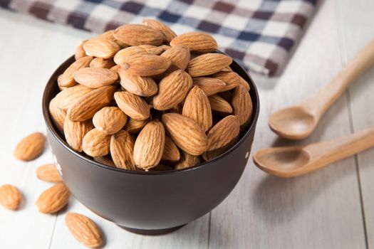 Almonds in bowl on wooden background