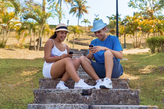 Couple of smiling young people sitting, each with a cellphone in their hands