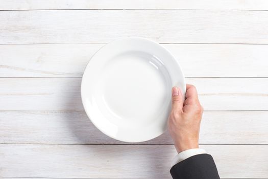 Business lunch and healthy food theme: man's hand holding a white empty plate