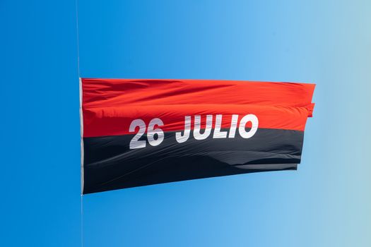 Flag of July 26, with two bands one red and one black and 26 Julio in the meddle with white letters, and a blue background