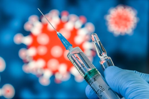 Coronavirus vaccine. A hand in medical gloves holds a vaccine and a syringe against the background of the image of a coronavirus. covid-19,