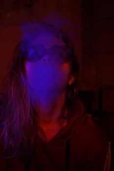 Close up vertical portrait of vaping girl in neon blue light