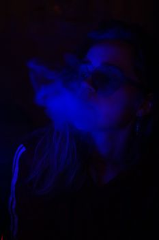 Close up vertical portrait of vaping girl in neon blue light